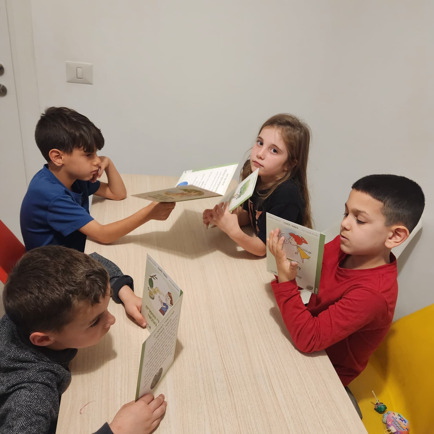 ילדים יושבים סביב שולחן ומתרגלים קריאה בקבוצה קטנה